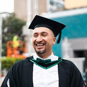 A man in a graduation gown smiling-- Moss Bollinger LLP
