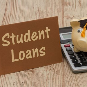 Student Loans” sign, calculator, and piggy bank with graduation cap on wooden surface- Moss Bollinger LLP