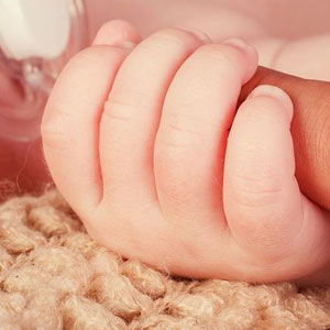 A newborn baby's hand in her mother’s hand - Moss Bollinger LLP