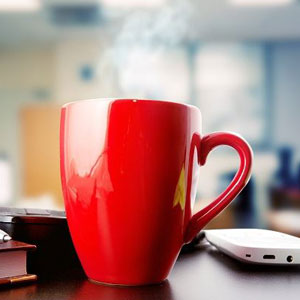 A red coffee mug on a desk-- Moss Bollinger LLP