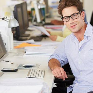 A man in glasses sitting at a desk with a computer- Moss Bollinger LLP
