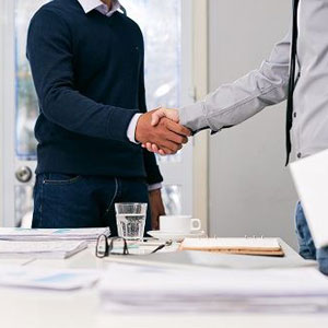 Two professionals shaking hands in a formal office setting- Moss Bollinger LLP