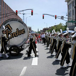 A marching band in a parade, featuring a large drum at the forefront, creating a rhythmic and vibrant atmosphere- Moss Bollinger LLP