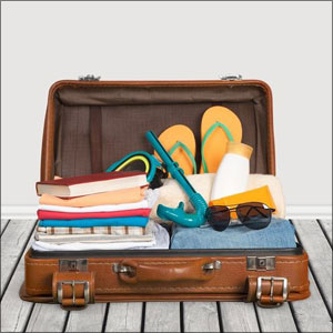 An open suitcase filled with clothes, shoes, sunglasses, and various items for travel or vacation- Moss Bollinger LLP