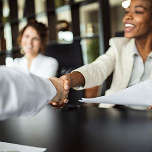 Two professionals shaking hands during a meeting, symbolizing a successful business agreement- Moss Bollinger LLP
