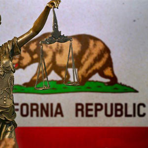 A metallic statue of justice holding scales against the California Republic flag- Moss Bollinger LLP