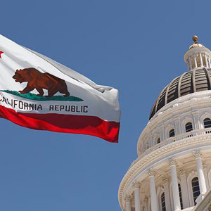 California flag flying in front of the Capitol building, symbolizing state pride and government- Moss Bollinger LLP