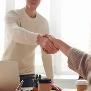 A man shaking hands with another person at a desk- Moss Bollinger LLP