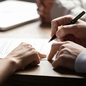 Two individuals signing a contract on a table, symbolizing a formal agreement between parties- Moss Bollinger LLP