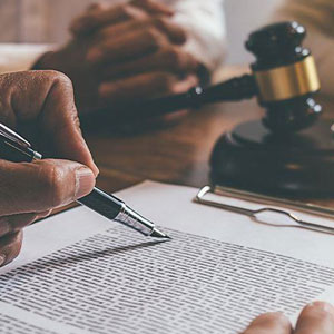 A man signing a contract with a pen and a gavel, symbolizing the legal process and agreement- Moss Bollinger LLP