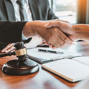 Two individuals shaking hands across a desk- Moss Bollinger LLP