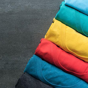 A collection of colorful t-shirts arranged in a stack on a dark surface- Moss Bollinger LLP
