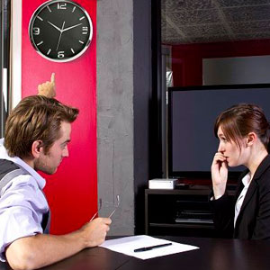 Two people in a meeting, with a clock and TV in the background- Moss Bollinger LLP