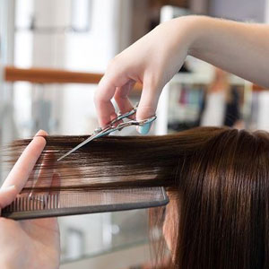 A stylist expertly trims a woman's hair using sharp scissors, ensuring a precise and stylish cut- Moss Bollinger LLP