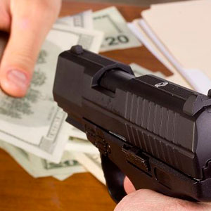 A person holding a gun and money on a table- Moss Bollinger LLP