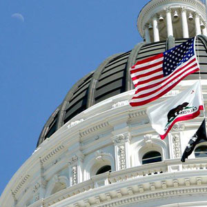 Neoclassical US Capitol dome, flags flutter, American flag & California state flag, crescent moon, grand architectural elegance- Moss Bollinger LLP
