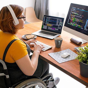 A woman in a wheelchair using a computer to access information and engage in online activities- Moss Bollinger LLP