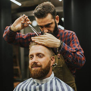 A man getting a haircut from another man in a professional salon- Moss Bollinger LLP