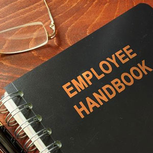 An employee handbook on a desk with glasses, providing essential guidelines for employees- Moss Bollinger LLP