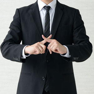A suited person making an ‘X’ sign, symbolizing prohibition or warning. Torso visible, face hidden- Moss Bollinger LLP