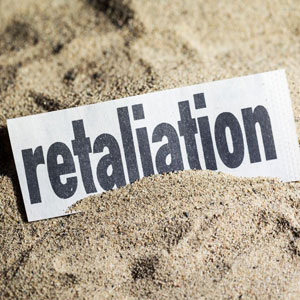 A torn piece of paper lies on sandy ground, bearing the word “retaliation” in bold black letters- Moss Bollinger LLP