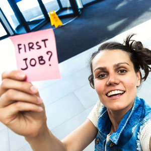 A woman holds a pink sticky note with the words “FIRST JOB?” written on it- Moss Bollinger LLP