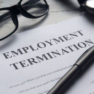 A termination letter, glasses, and pen on a table symbolize employment termination - Moss Bollinger LLP
