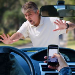 man holding a cellphone while driving, posing a dangerous distraction on the road - Moss Bollinger LLP