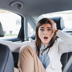 A surprised woman in the backseat of a car - Moss Bollinger LLP