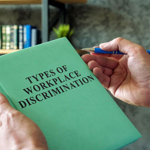 A man holding a book “type of workplace descrimination” - Moss Bollinger LLP