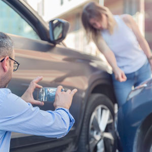 A man capturing a photo of a car accident scene - Moss Bollinger LLP