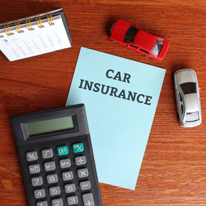 A car insurance paper calculator, cars and calendar on a desk - Moss Bollinger LLP
