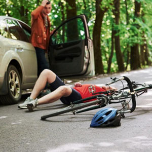 A man with a broken leg sits on the road next to a car - Moss Bollinger LLP