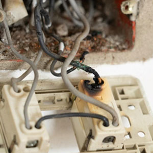 A close-up of a broken electrical outlet with exposed wires. - Moss Bollinger LLP
