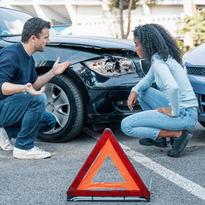 A man and woman discussing a car accident, exchanging information and assessing the damage. - Moss Bollinger LLP