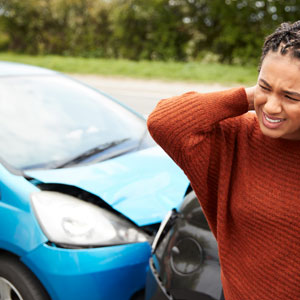 A woman in distress, clutching her head in agony, following a car accident. - Moss Bollinger LLP