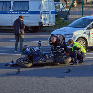 Two men standing near a motorcycle accident scene, assessing the situation and discussing the incident. - Moss Bollinger LLP